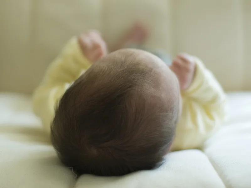ベビーベッドで眠る赤ちゃんの後ろ姿
